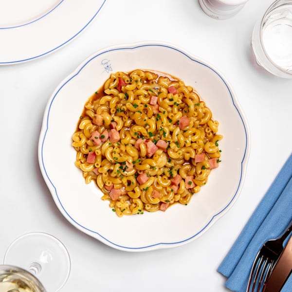 Monsieur Bistro's French macaroni with ham and chives in a white bowl with blue trim.